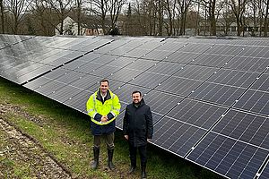 Stadtwerkegeschäftsführer Sebastian Kirchmann (l.) und Aufsichtsratsvorsitzender Dimitrios Axourgos stehen vor einem großen Solarpanel auf der Solaranlage an der Ostberger Straße.